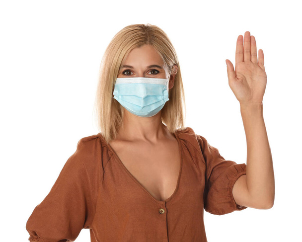 Woman in protective mask showing hello gesture on white background. Keeping social distance during coronavirus pandemic - Fotografie, Obrázek