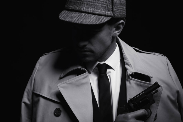 Old fashioned detective with revolver on dark background, black and white effect - Foto, imagen