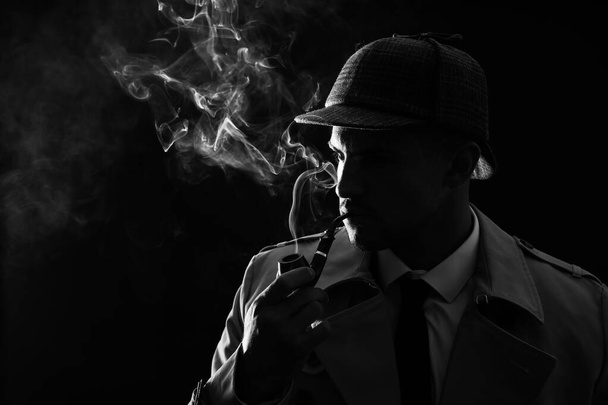 Old fashioned detective smoking pipe on dark background, black and white effect - Foto, imagen