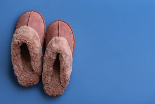 Pair of stylish soft slippers on blue background, flat lay. Space for text - Фото, изображение