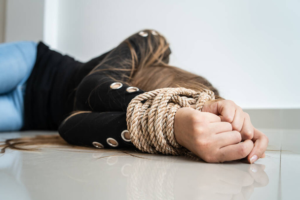Close up on hands of Unknown caucasian woman or minor girl ξαπλωμένη αναίσθητη στο πάτωμα με δεμένα χέρια - Ανθρώπινα δικαιώματα απαγωγή σεξουαλική βία έννοια επιλεκτική εστίαση - Φωτογραφία, εικόνα