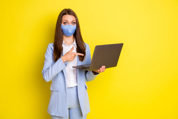 Shocked economist girl in respiratory mask work remote point finger laptop present covid quarantine news wear blue blazer jacket pants trousers isolated bright shine color background - Foto, Imagen