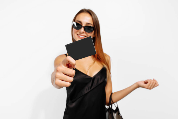 Elegant young business woman, in a black dress, holding shopping bags and a credit card, on a white background, Black Friday, shopping - Valokuva, kuva