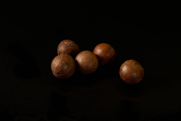 five macadamia nuts isolated on black background - Foto, afbeelding