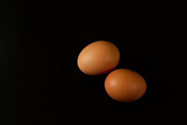 Two brown chicken eggs isolated on black background - Photo, Image