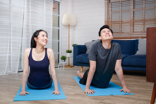 Las parejas asiáticas hacen ejercicio juntas en casa en la sala de estar. Para mantener una buena salud y la distancia social Durante COVID 19 - Foto, imagen