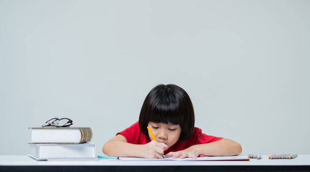 Dívka dělá domácí úkol, dítě psaní papíru na bílém pozadí, vzdělávací koncept - Fotografie, Obrázek