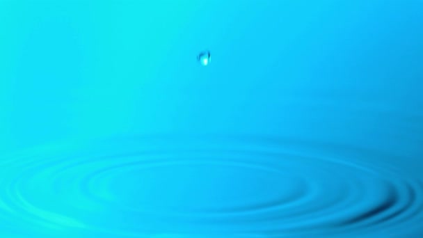 Una gota de agua cayendo en la piscina causando ondulaciones - cámara lenta - Metraje, vídeo