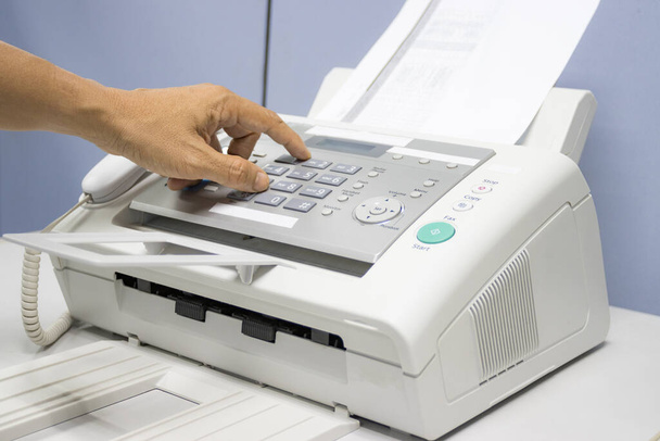 mano uomo stanno utilizzando un fax in ufficio, attrezzature per la trasmissione dei dati. - Foto, immagini