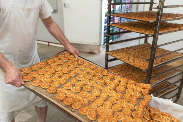 O padeiro coloca os pretzels salgados frescos retirados do forno.Bandejas com muitos pretzels no fundo. - Foto, Imagem