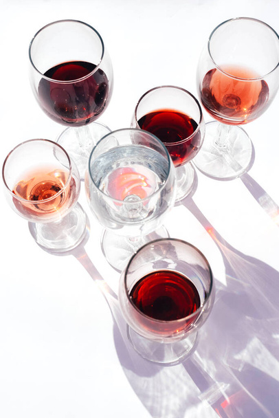 Okulary z czerwonym, białym i różowym winem na białym tle. Zdjęcie poziome. - Zdjęcie, obraz