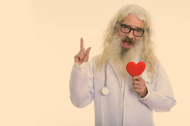 Студийный снимок красивого старшего врача с длинной белой кудрявой бородой и волосами на белом фоне - Фото, изображение
