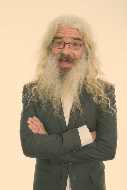 Studio shot of handsome senior businessman with long white curly beard and hair isolated against white background - Foto, afbeelding