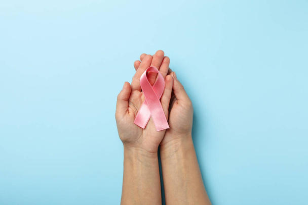 Female hands with pink awareness ribbon on blue background - Photo, image