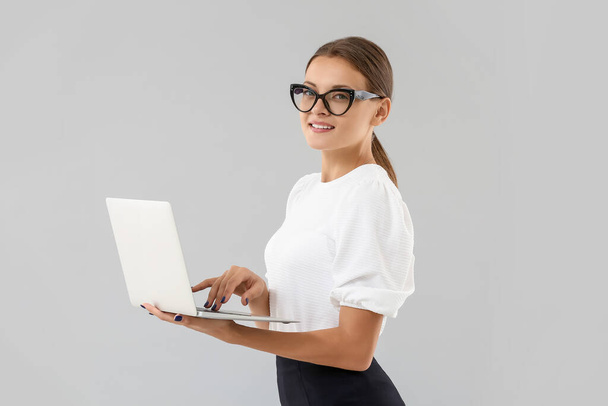 Portrait of young businesswoman with laptop on light background - Φωτογραφία, εικόνα