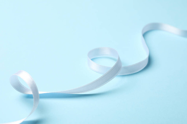 White curly ribbon on blue background, close up - 写真・画像