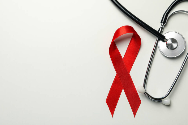Red awareness ribbon and stethoscope on white background - Zdjęcie, obraz