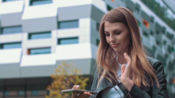 Atrakcyjna dziewczyna, studentka, w nowoczesnych ubraniach Używa telefonu komórkowego do słuchania dobrej muzyki nastroju, meloman stawia ulubioną piosenkę, szczęśliwa kobieta korzysta z roamingu, szybkie połączenie 5G - Zdjęcie, obraz