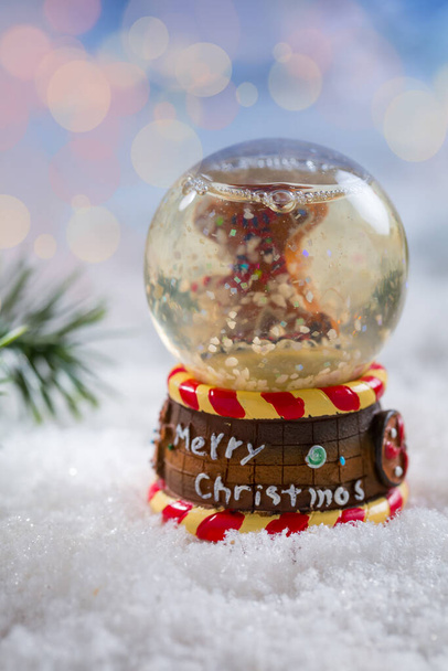 Снігова куля з гілкою на снігу з розмитим тлом. Символ зими та Різдва
. - Фото, зображення