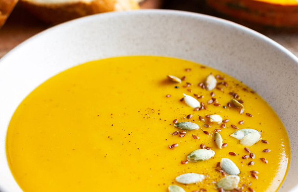Pumpkin cream soup with pumpkin seeds close-up. Autumn breakfast. Diet food. - Foto, afbeelding