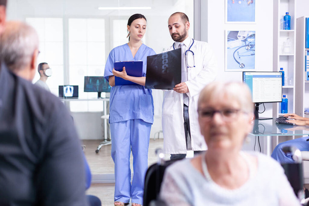 Krankenschwester im Gespräch mit Arzt auf Röntgenbild - Foto, Bild
