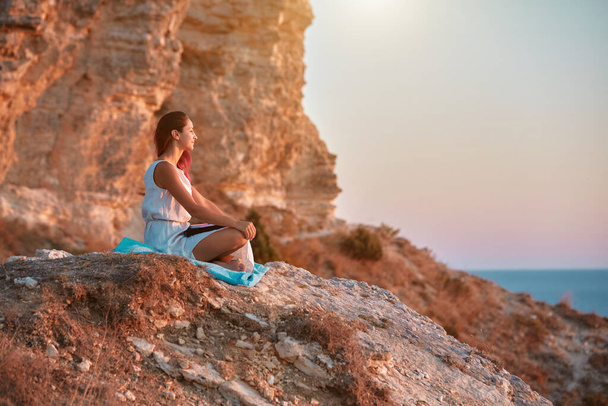Girl sitting on rock and enjoying nature. Sunset and fresh air. Self absorbed and contemplation time idea, copy space - Foto, immagini