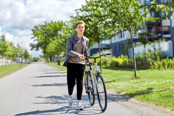 jovem com bicicleta andando ao longo da rua da cidade - Foto, Imagem