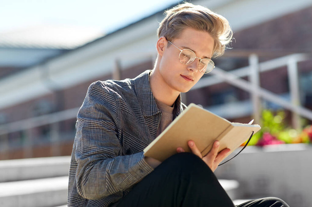 young man with notebook or sketchbook in city - Foto, Bild