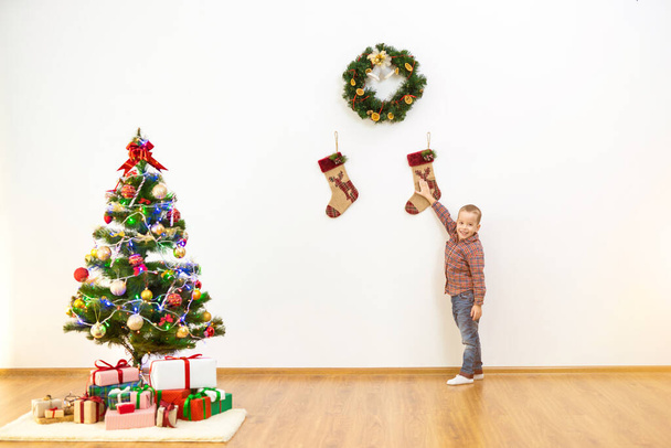 Chłopiec stoi obok świątecznej dekoracji na ścianie - Zdjęcie, obraz