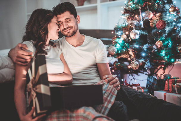 Šťastný pár vybalí dárkovou krabici u vánočního stromečku. večerní čas - Fotografie, Obrázek