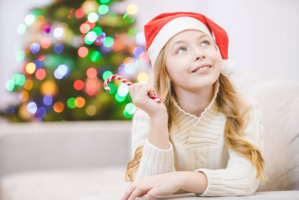 Das glückliche Mädchen mit dem Weihnachtsmann-Hut lag neben dem Weihnachtsbaum - Foto, Bild