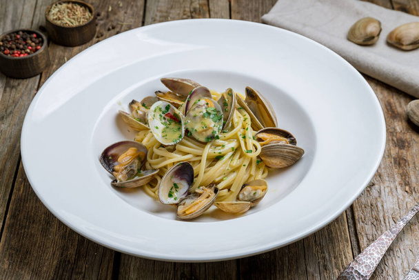 Spaghetti with vongole in wine sauce on wooden background - Foto, Imagem