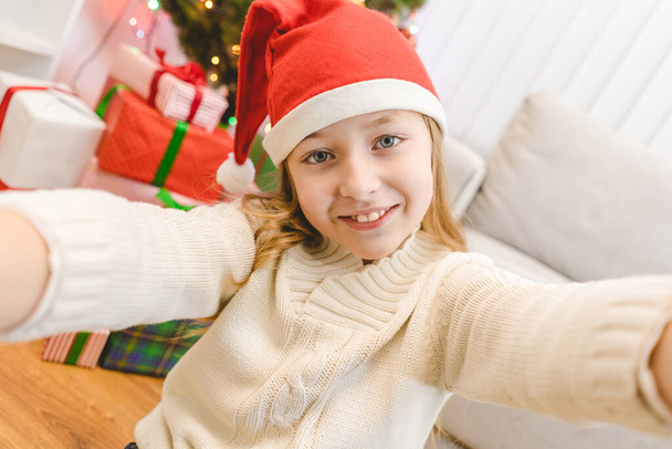 La bambina carina in cappello di Babbo Natale tenere una macchina fotografica - Foto, immagini