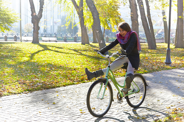 egy fiatal lány megtanulja, hogy kerékpározni őszi parkban. háttérvilágítás. - Fotó, kép