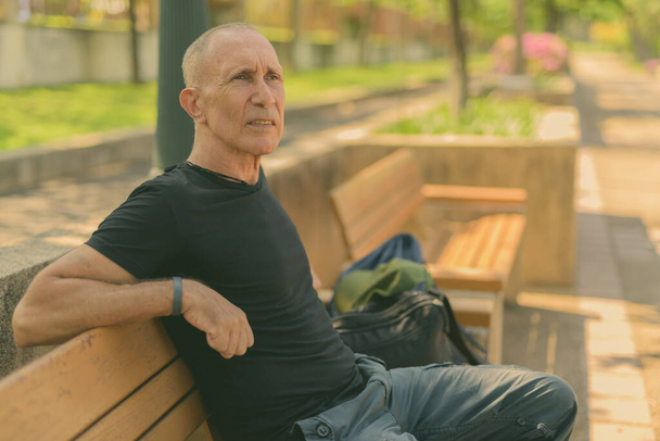Portrait of bald senior tourist man relaxing at the park outdoors - Photo, Image
