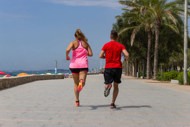 Fitness pár futó tengerparti sétányon.Atlétikai pár koncepció.Sport és egészséges életmód ötlet. - Fotó, kép