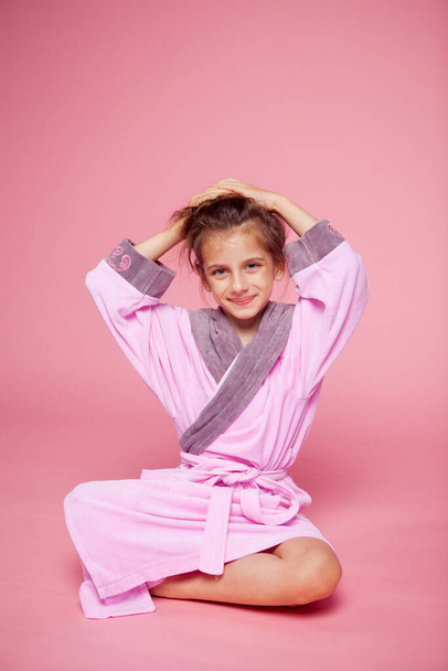 schattig meisje gekleed in een badjas badstof recht haar haar - Foto, afbeelding