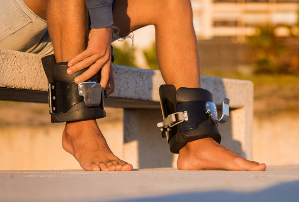 Άντρας που φοράει μπότες αντιβαρύτητας ή αντιστροφής έτοιμες για ανάποδη ανάρτηση στην οριζόντια μπάρα. Αθλητικός εξοπλισμός.  - Φωτογραφία, εικόνα