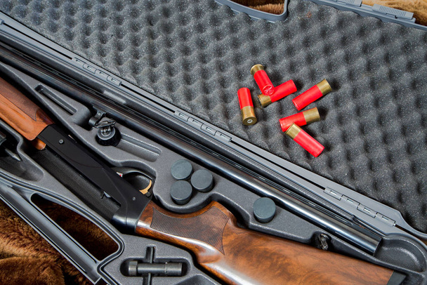 uma espingarda de caça desmontada de calibre 12 e três cartuchos vermelhos em um estojo de arma cinza - Foto, Imagem