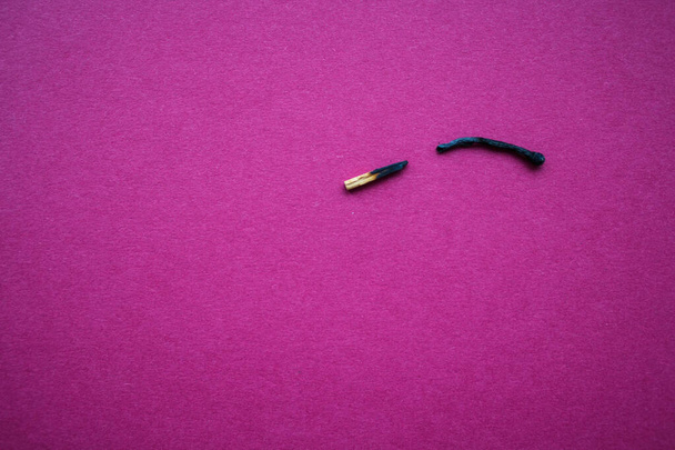spalona zapałka rozbita na pół na liliowym tle - Zdjęcie, obraz