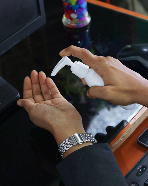 higiena, opieka zdrowotna i koncepcja bezpieczeństwa - Indianka stosująca antybakteryjny środek do dezynfekcji rąk w biurze - Zdjęcie, obraz