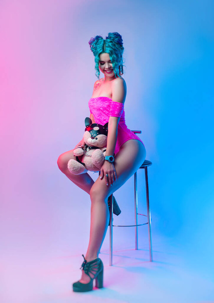 una donna con i capelli blu e un body rosa è seduta su uno sgabello da bar - Foto, immagini