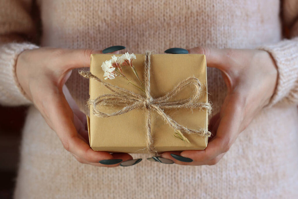 Young caucasian woman holding a gift wrapped in kraft paper. Zero waste concept - Φωτογραφία, εικόνα