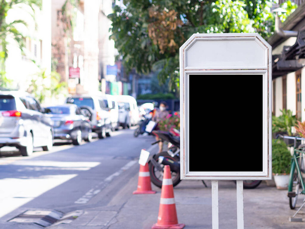 Черный рекламный щит с белой рамкой и вертикальной укладкой на обочине дороги. Вывеска для средств массовой информации, рекламы, маркетинга. Пространство для текста - Фото, изображение