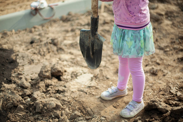 A child with a shovel takes soil. Planting plants in the park. The girl is burying a seedling.  - Φωτογραφία, εικόνα