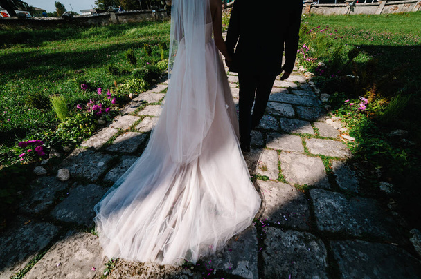 Beautiful portrait wedding couple are walking backs near ancient architecture, old building, vintage palace outdoor. Atmosphere street. bottom, back view. - Foto, imagen