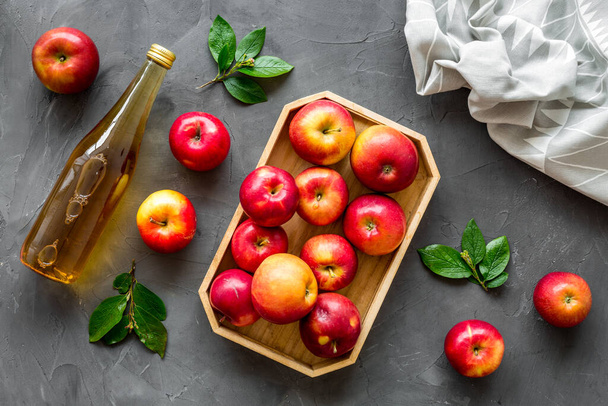 Apple cider vinegar in glass bottle and wooden tray with red apples - Foto, Imagen