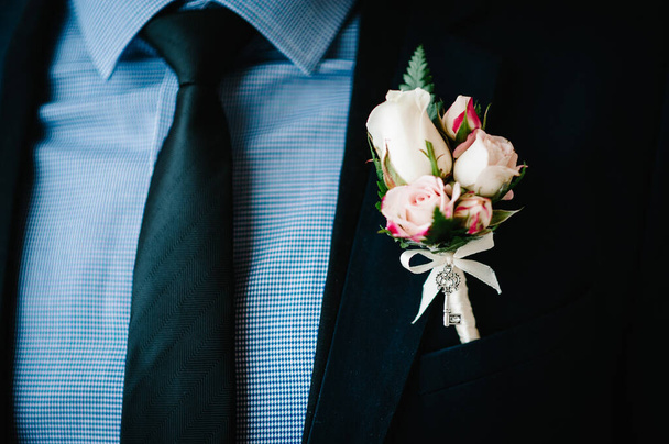 Man in a suit and tie close up. On the jacket - buttonhole, boutonniere. Morning preparation groom at home. Fashion photo of a man. - 写真・画像