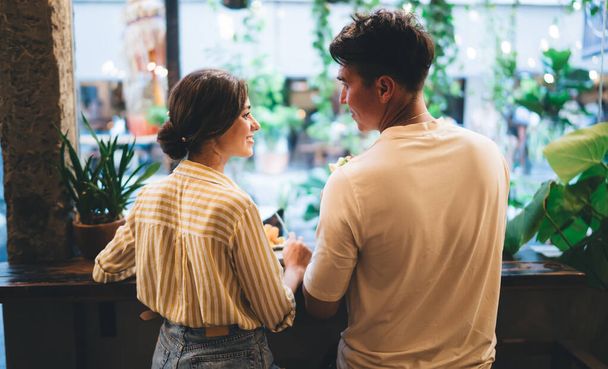 Side view of young man and woman in casual clothes standing near counter in modern cafeteria and looking at each other - Фото, зображення