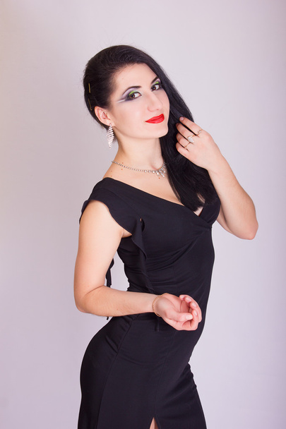 Beautiful slim young brunette woman in evening black dress and jewelry - Foto, imagen